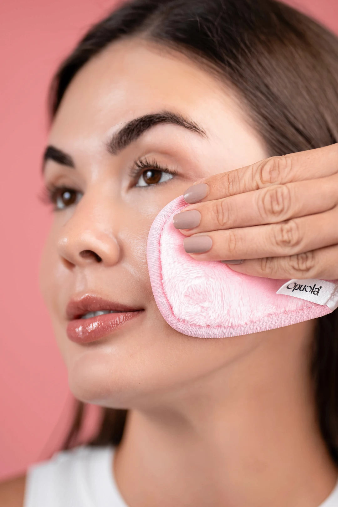 Close-up of woman using Opuola reusable cleansing pad to remove makeup and prepare under-eye area before applying hydrating eye patches