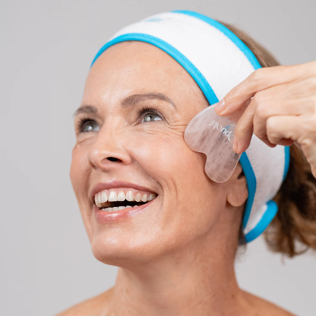 Woman using OPUOLA Nohea Quartz Gua Sha on under-eye area as part of a skin-care and hydration ritual