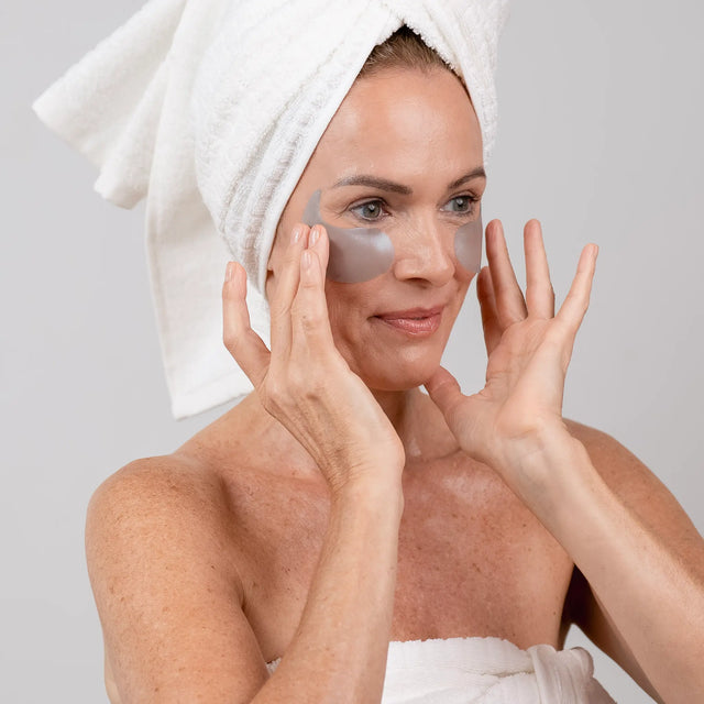 Woman in her 40s applying Opuola under-eye patches to reduce dark circles and refresh tired-looking eyes