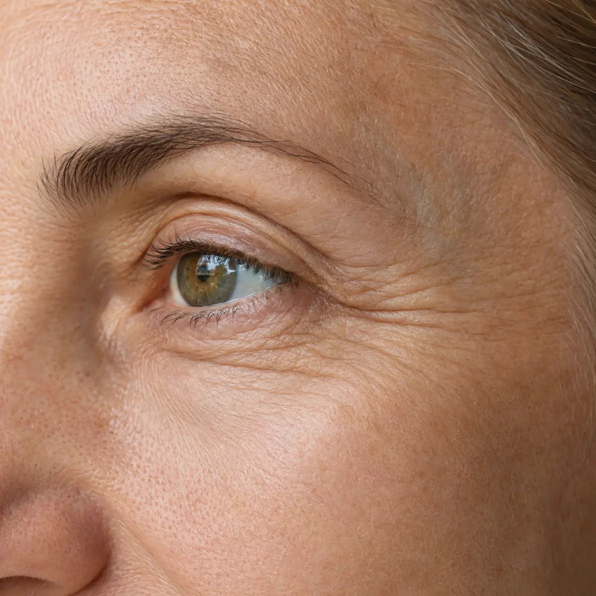 Close-up of natural under-eye fine lines and crow's feet on mature skin